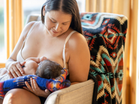 Indigenous mother breastfeeding baby in chair