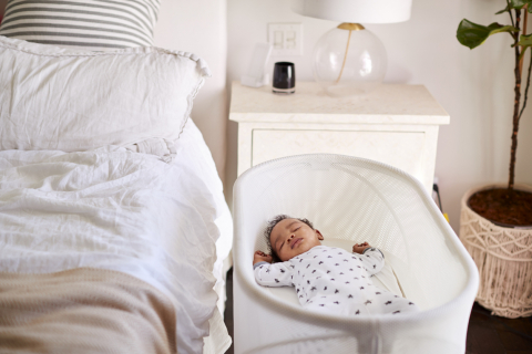 Baby sleeping in bassinet by mother's bed